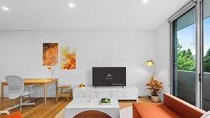 Een moderne woonkamer met een televisie, een bureau, een bank en een eettafel.
