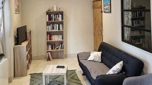 Een woonkamer met een bank, een salontafel, een boekenkast en een televisie.