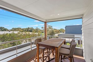 A balcony with a table and chairs, a railing, and a view of the surrounding area. - Golf Course Front Stylish Townhouse w/ Pool Access (Cowes)