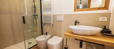 Un baño moderno con ducha de vidrio, lavamanos blanco y retrete.