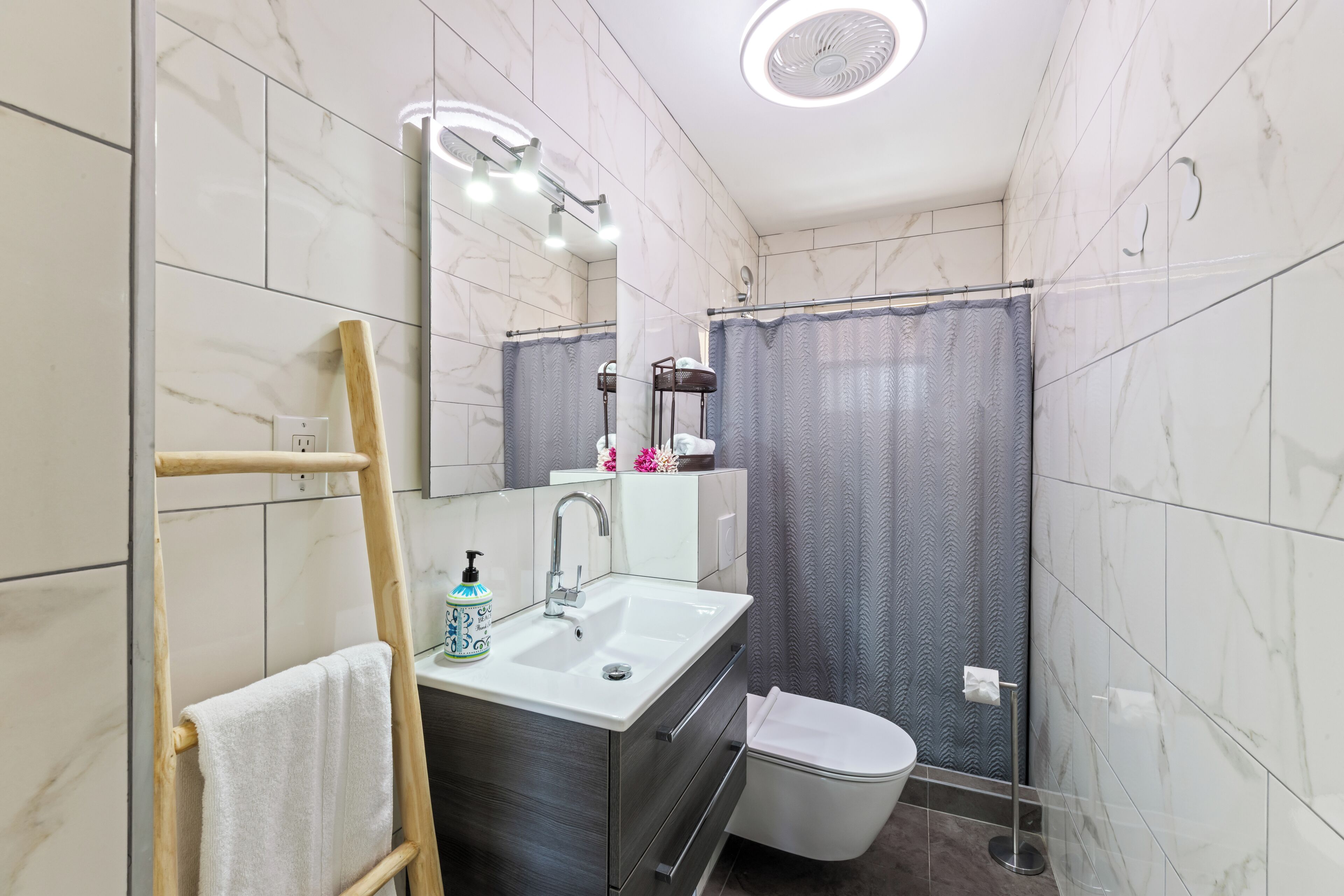 A bathroom with a sink, mirror, towel rack, shower curtain, and toilet.
