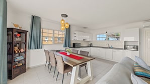 Una cocina moderna con armarios blancos, una mesa de comedor con sillas y un sofá.