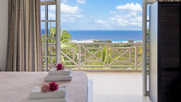 Habitación de hotel con cama, balcón y vista al océano, además de televisión.