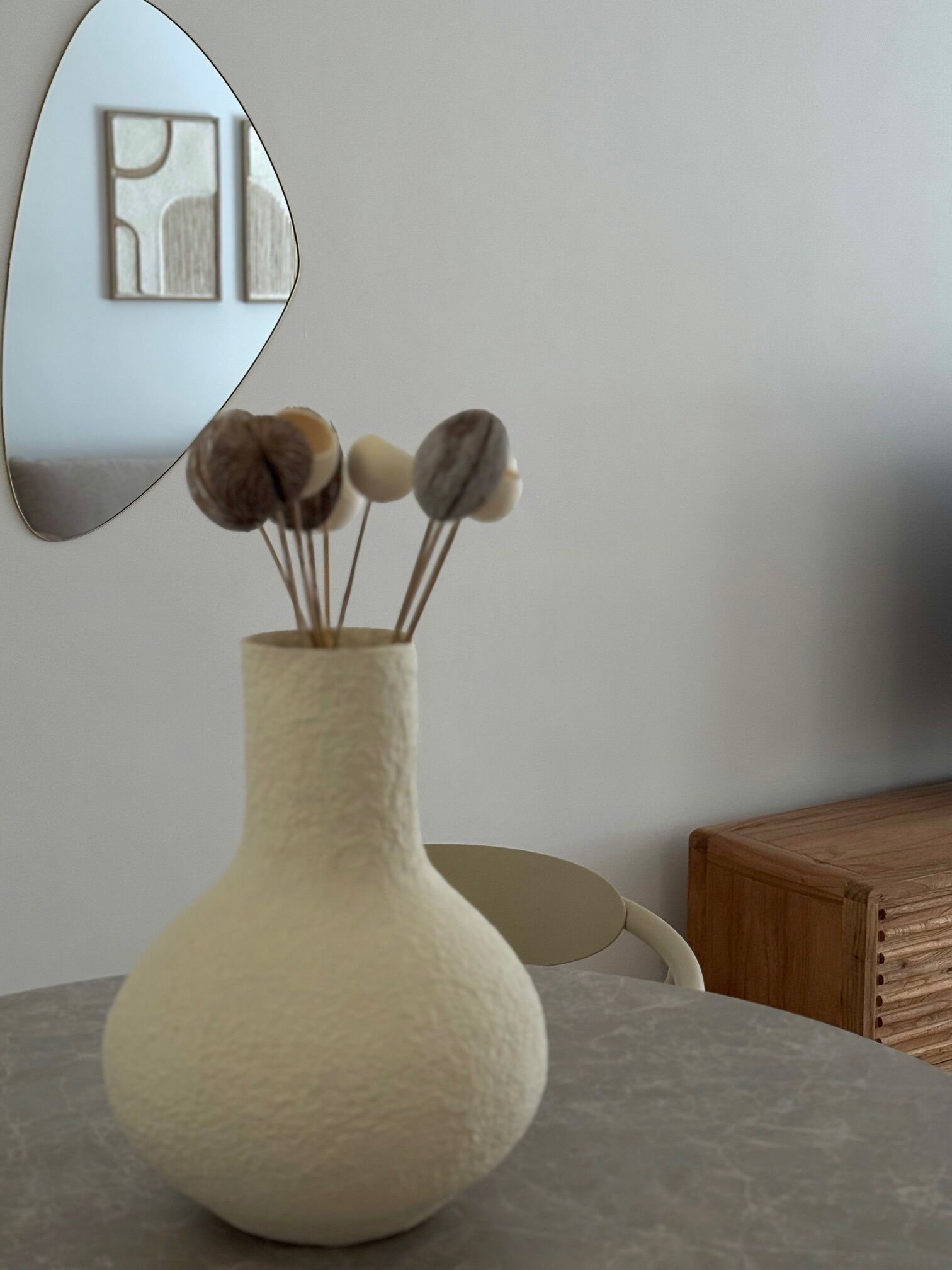 A textured vase with a few decorative items on a table.