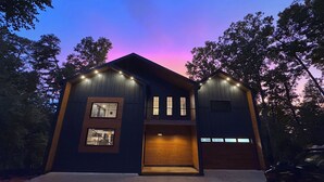 Una moderna casa a due piani con garage, finestre illuminate e vialetto.