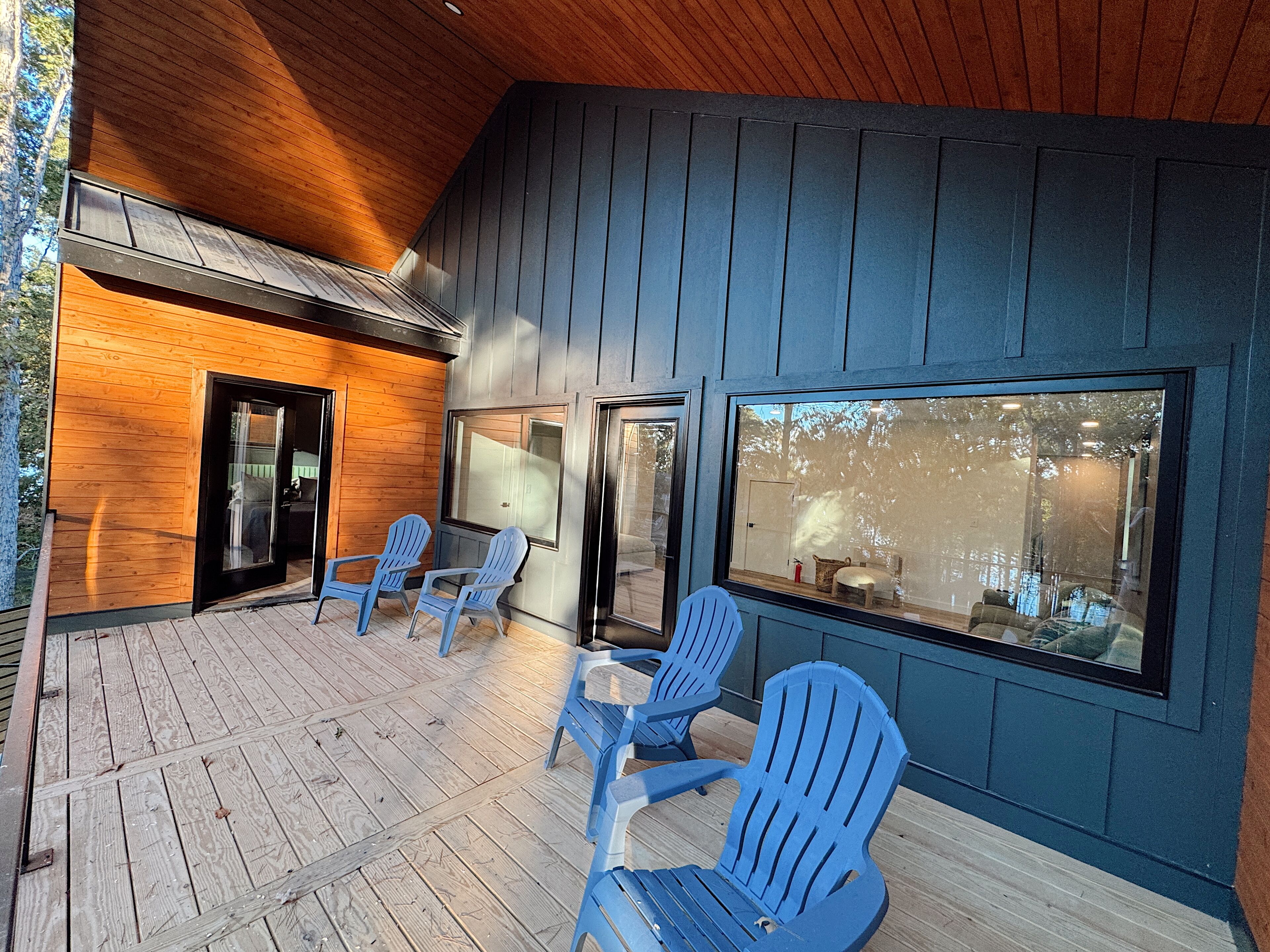 Un espace extérieur abrité, doté d’un plancher en bois et de chaises bleues.