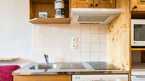 A kitchen with wooden cabinets, a stainless steel sink, a built-in stove, and a dishwasher. - Cosy Apartment in the Mountains in Giez (Giez)
