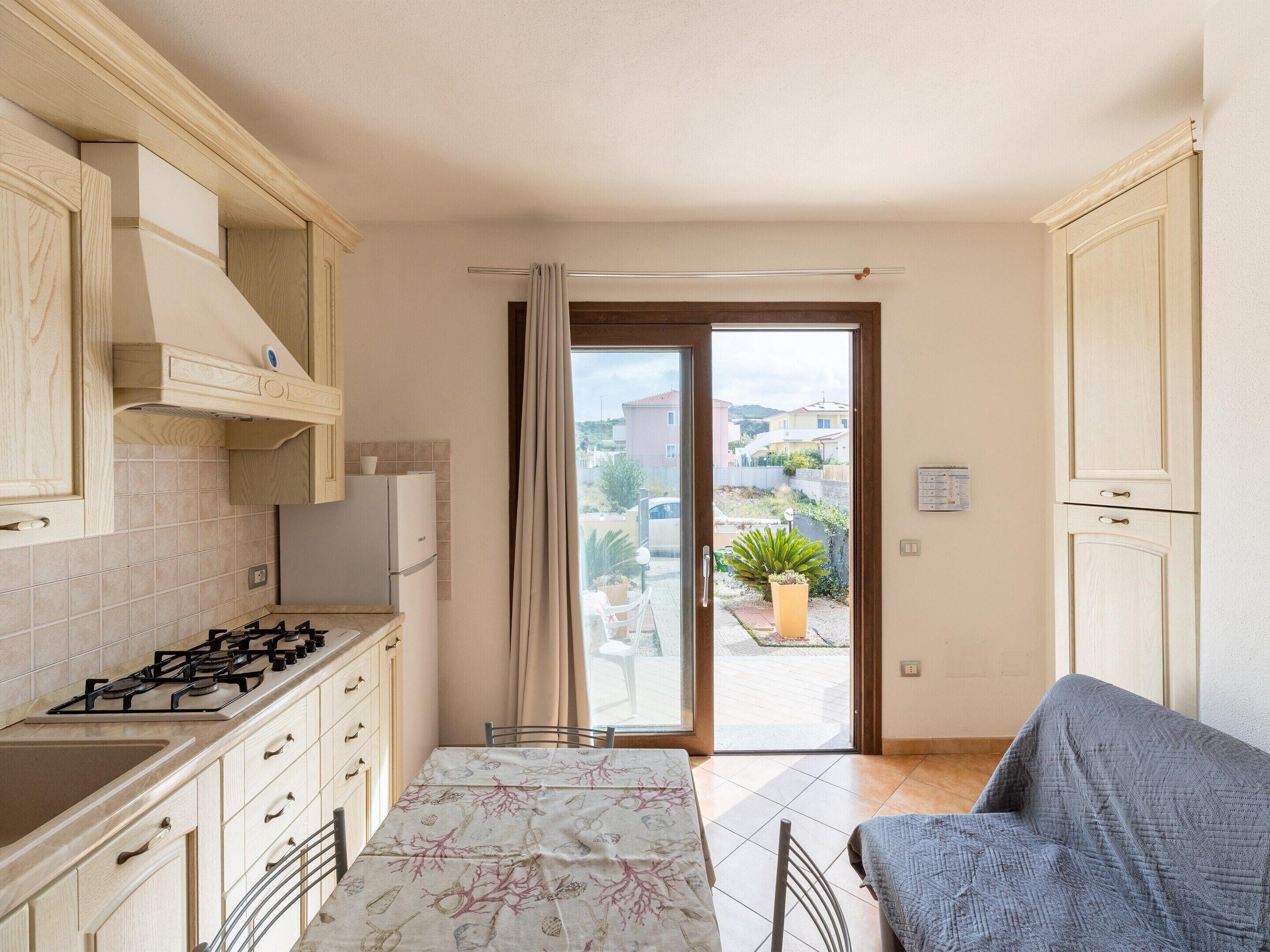 A compact kitchen with a gas stove, cabinets, and a view of the outside.