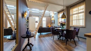 Une pièce spacieuse avec un plancher en bois, un coin repas comprenant une table et des chaises, un canapé et un escalier.