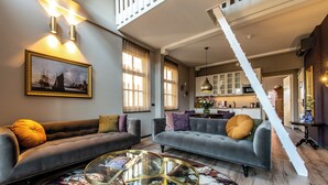 Un salon spacieux avec deux canapés, une table basse en verre et un escalier menant à l’étage supérieur.