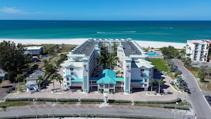Ein Strandhotel mit einem zentralen Atrium, mehreren Balkonen und einem Parkplatz.
