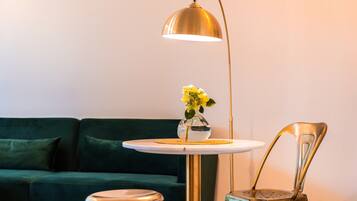 Ein modernes Wohnzimmer mit einem grünen Sofa, einem runden Tisch mit Blumenvase, einer Stehlampe und einem Sessel.