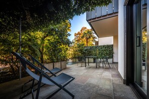 A patio with outdoor furniture, a wall with climbing plants, and a view of trees.