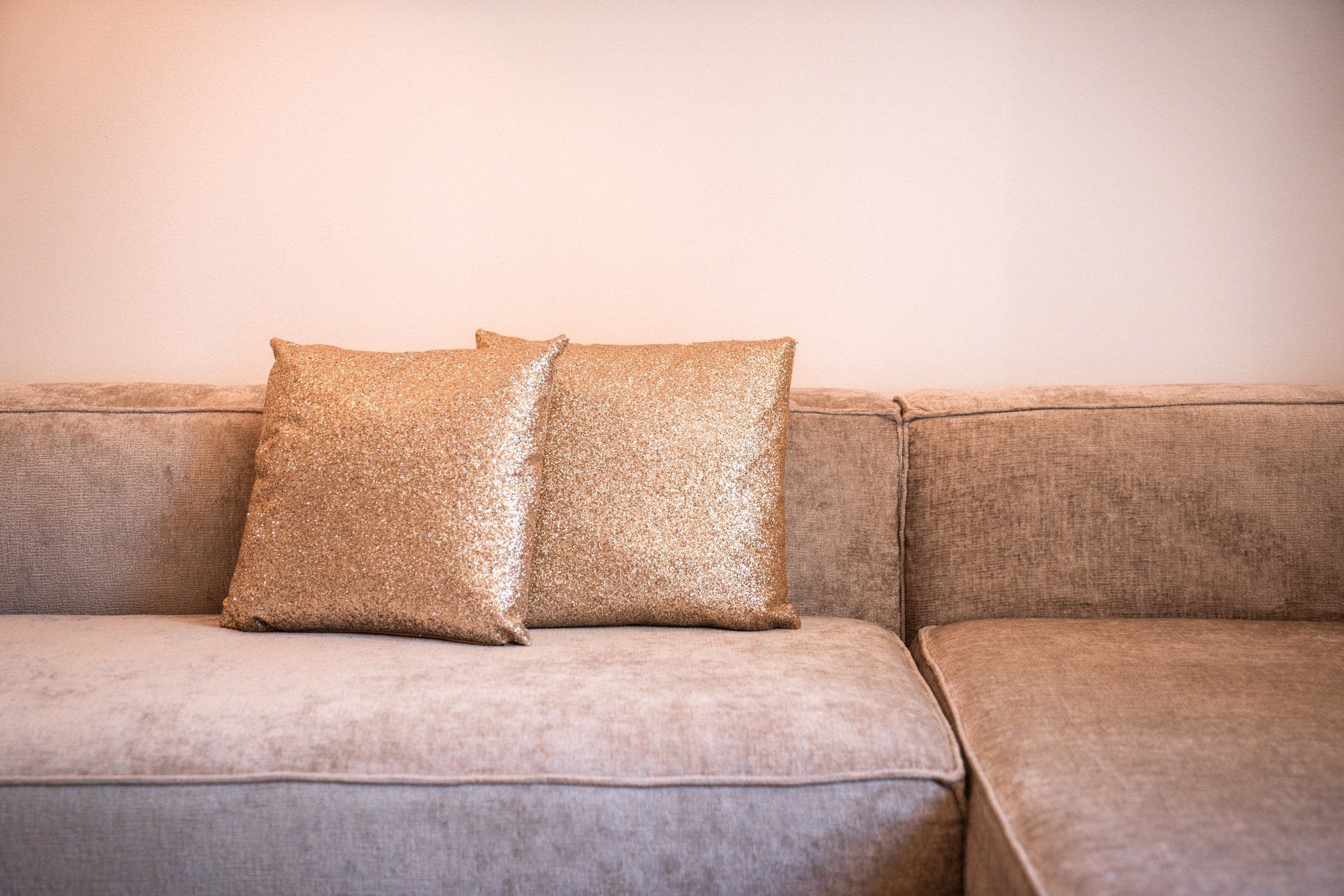A sofa with two glittery pillows.