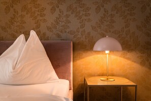 Un lit avec des oreillers et une table de chevet avec une lampe.