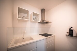 A kitchen with a white countertop, a sink, a stove, and a coffee machine. - 739F goldfinger+suites I Apartment Unique 15 (Lana)
