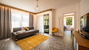 A modern living room with a sofa, a yellow rug, and a television. - 739F goldfinger+suites I Apartment Unique 15 (Lana)