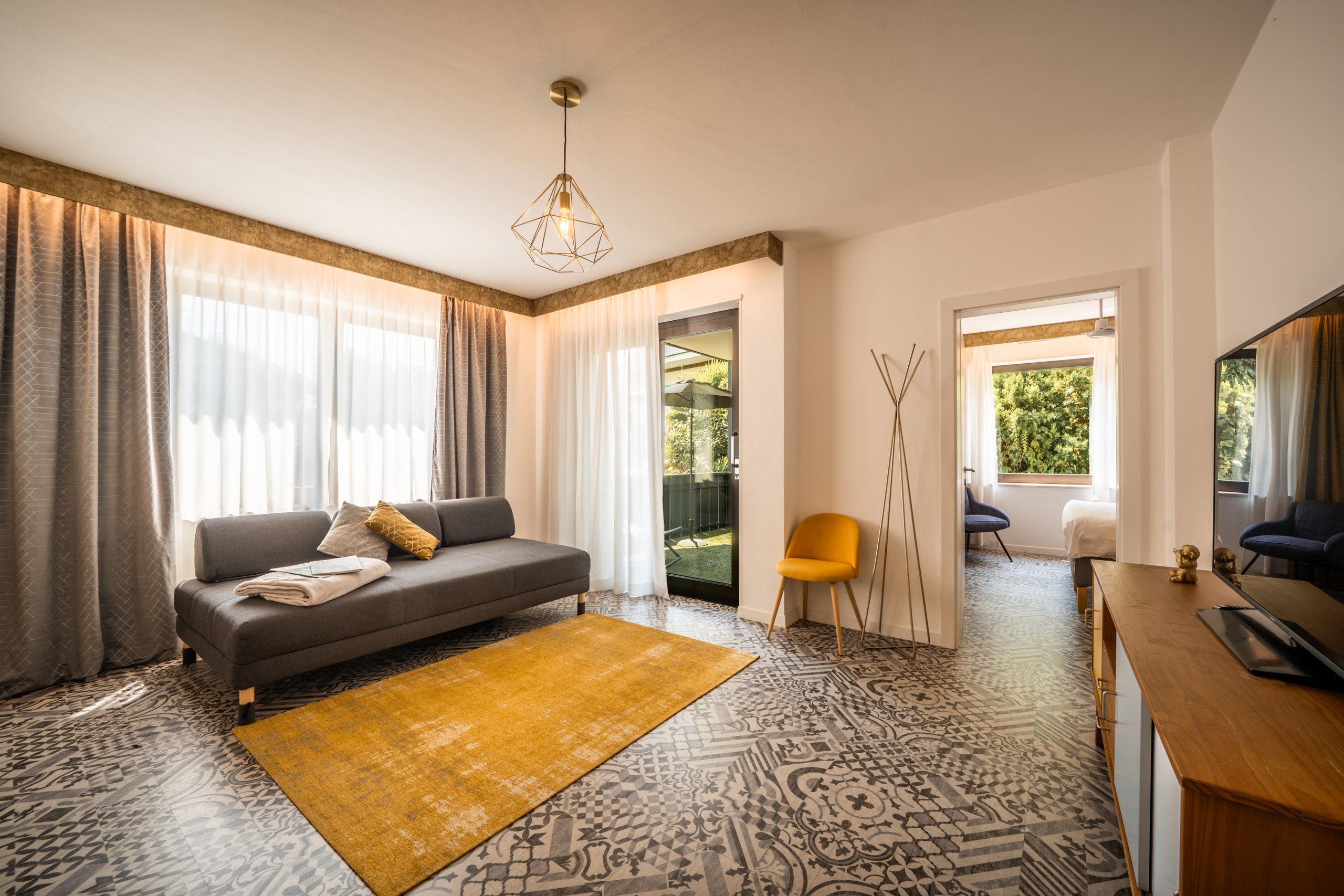 Een moderne woonkamer met een bank, een geel vloerkleed, en een eethoek met een tafel en stoelen.
