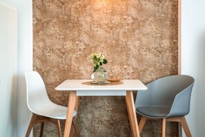 Une petite table avec deux chaises, un vase de fleurs et un mur à motifs en arrière-plan.