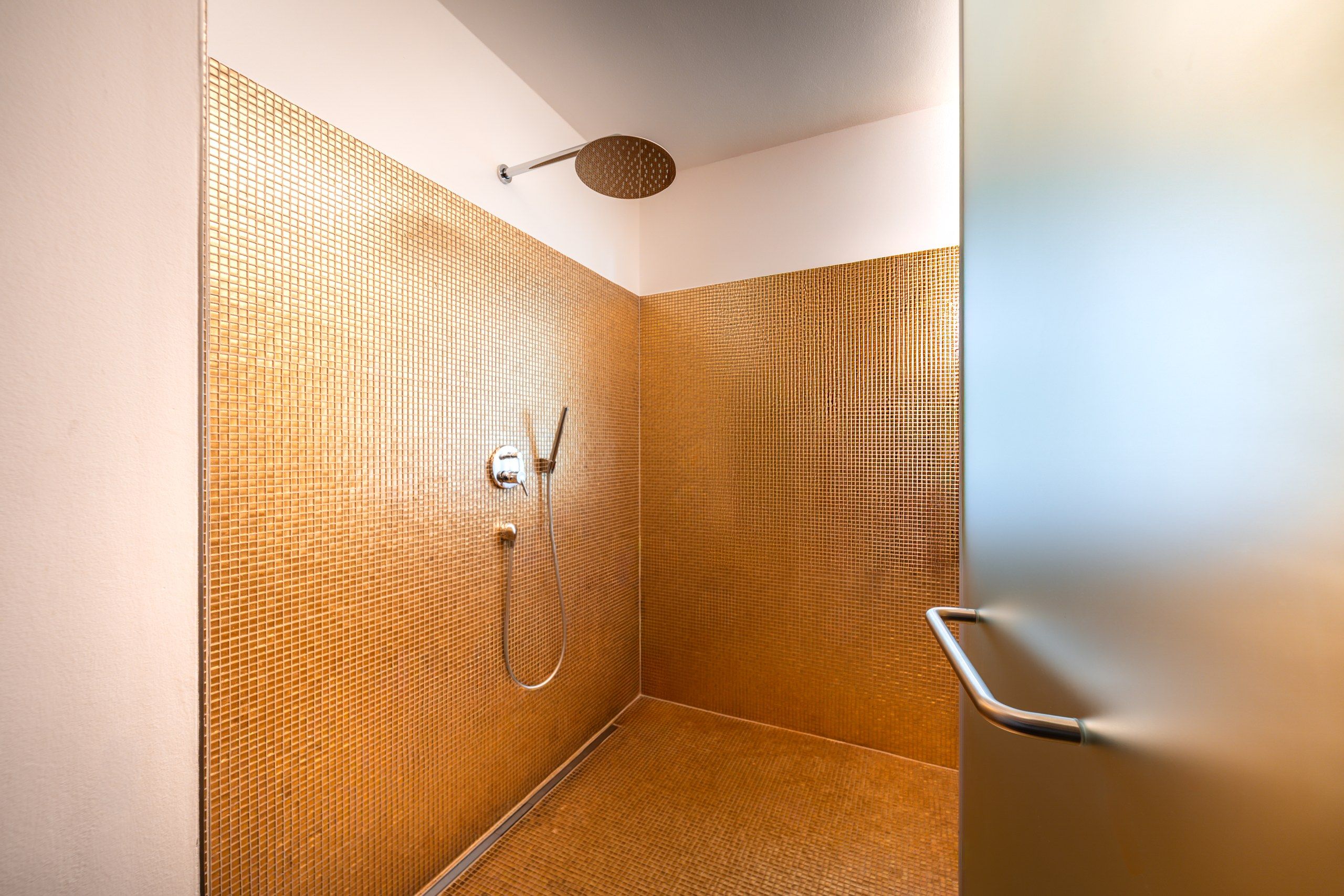 Eine Dusche mit einer Wand mit Struktur und einer Handbrause.