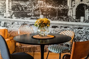 Ein runder Tisch mit Blumen in einer Vase, ein durchsichtiger Glasstuhl und gestreifter Polsterung.