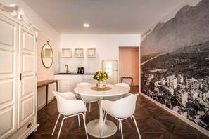 Une pièce moderne comprenant une table à manger, des chaises blanches, un coin cuisine et une fresque murale.
