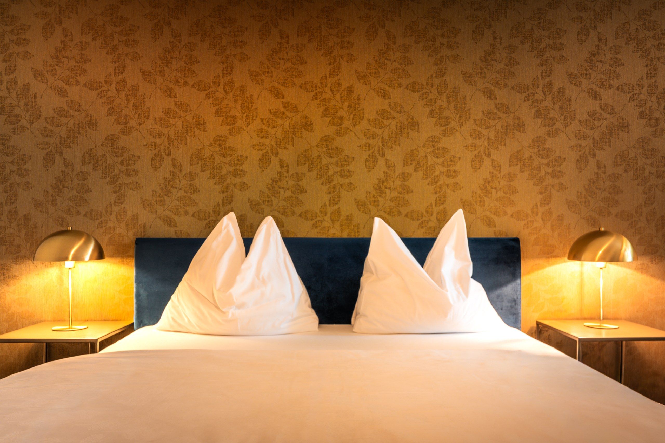 Ein Hotelzimmer mit einem Bett, zwei Nachttischlampen und einer Wand mit Muster.
