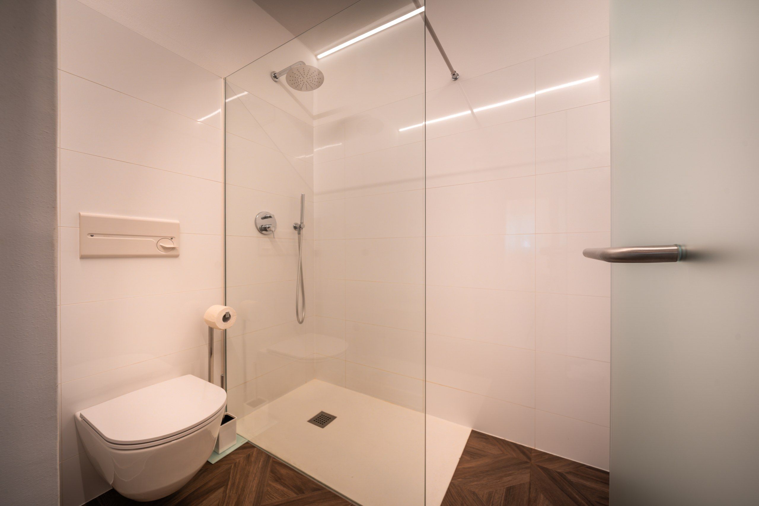 Een moderne badkamer met een douchecabine van glas, een toilet en een toiletbril met douchefunctie.