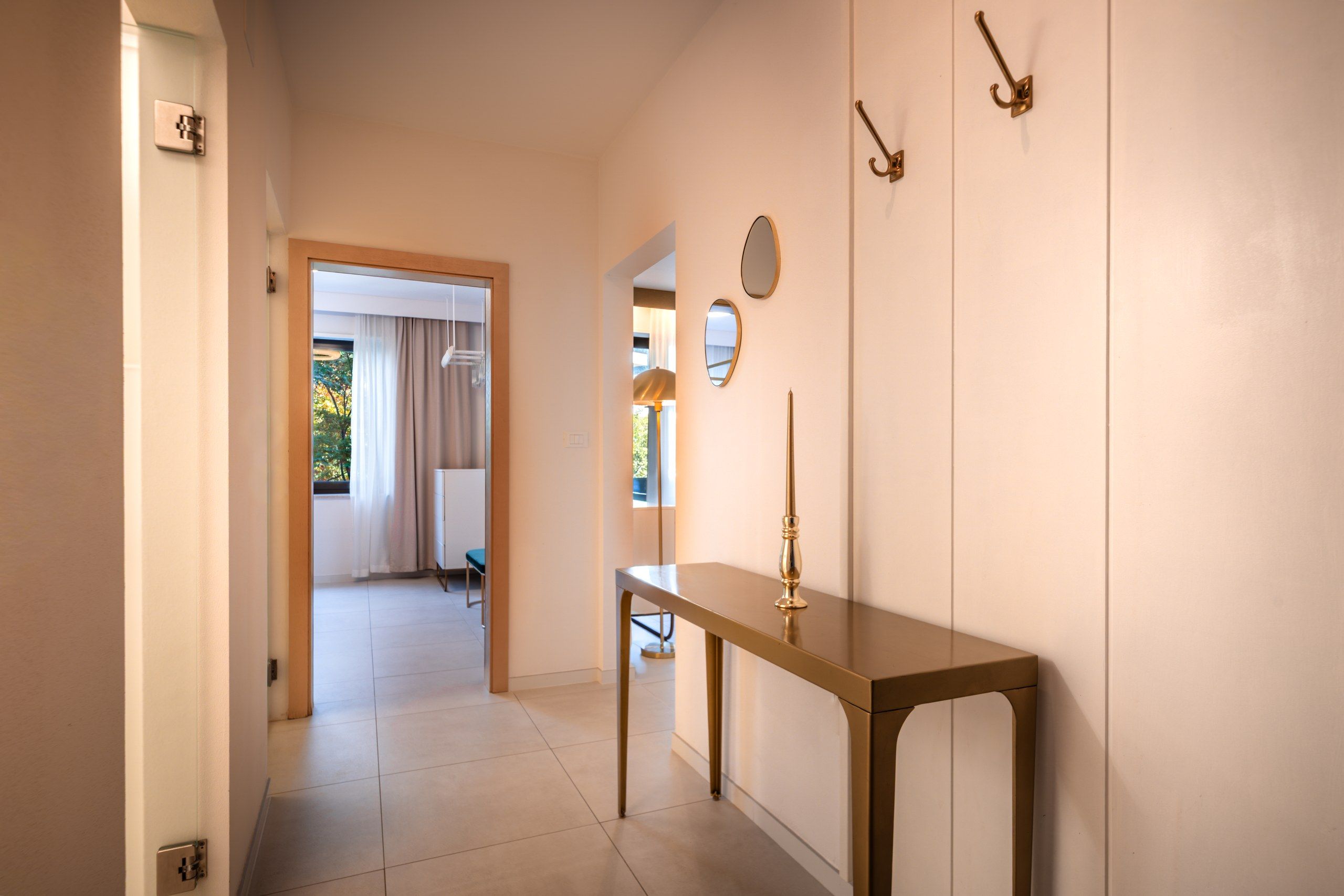 A hallway with a wooden table, a mirror, and wall-mounted hooks.