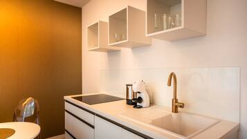 Een moderne badkamer met een witte wasbak, een koffieapparaat en een glazen kast erboven.