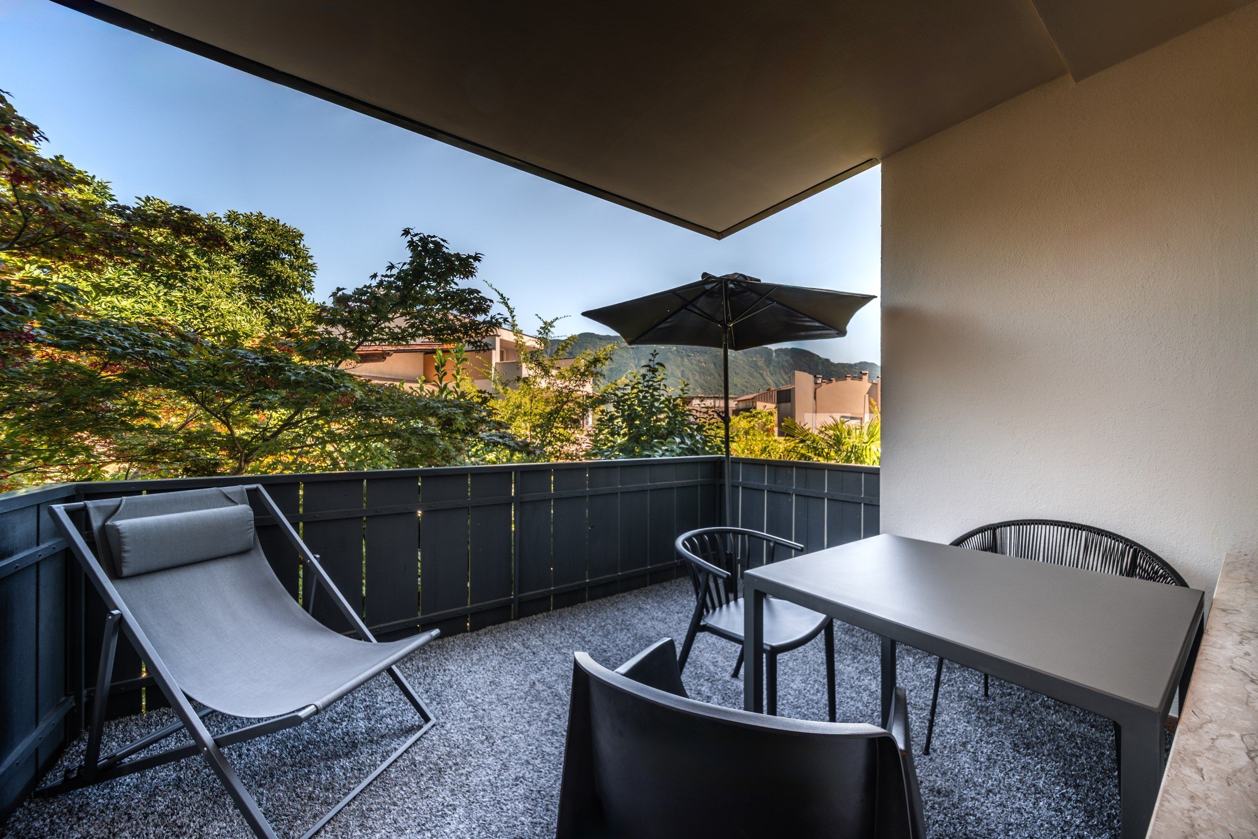 Een balkon met een tafel, stoelen en een parasol.