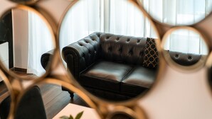 Una sala de estar moderna con un sofá de cuero negro, una mesa de centro y un espejo grande.