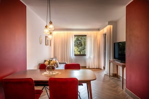 Ein moderner Essbereich mit einem Holztisch, roten Stühlen, einer Blumenvase und einem Fernseher auf einem Holzschrank.