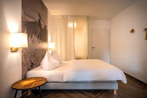 Ein Hotelzimmer mit einem Bett, einem kleinen Holztisch, zwei Wandlampen und einer Tür.