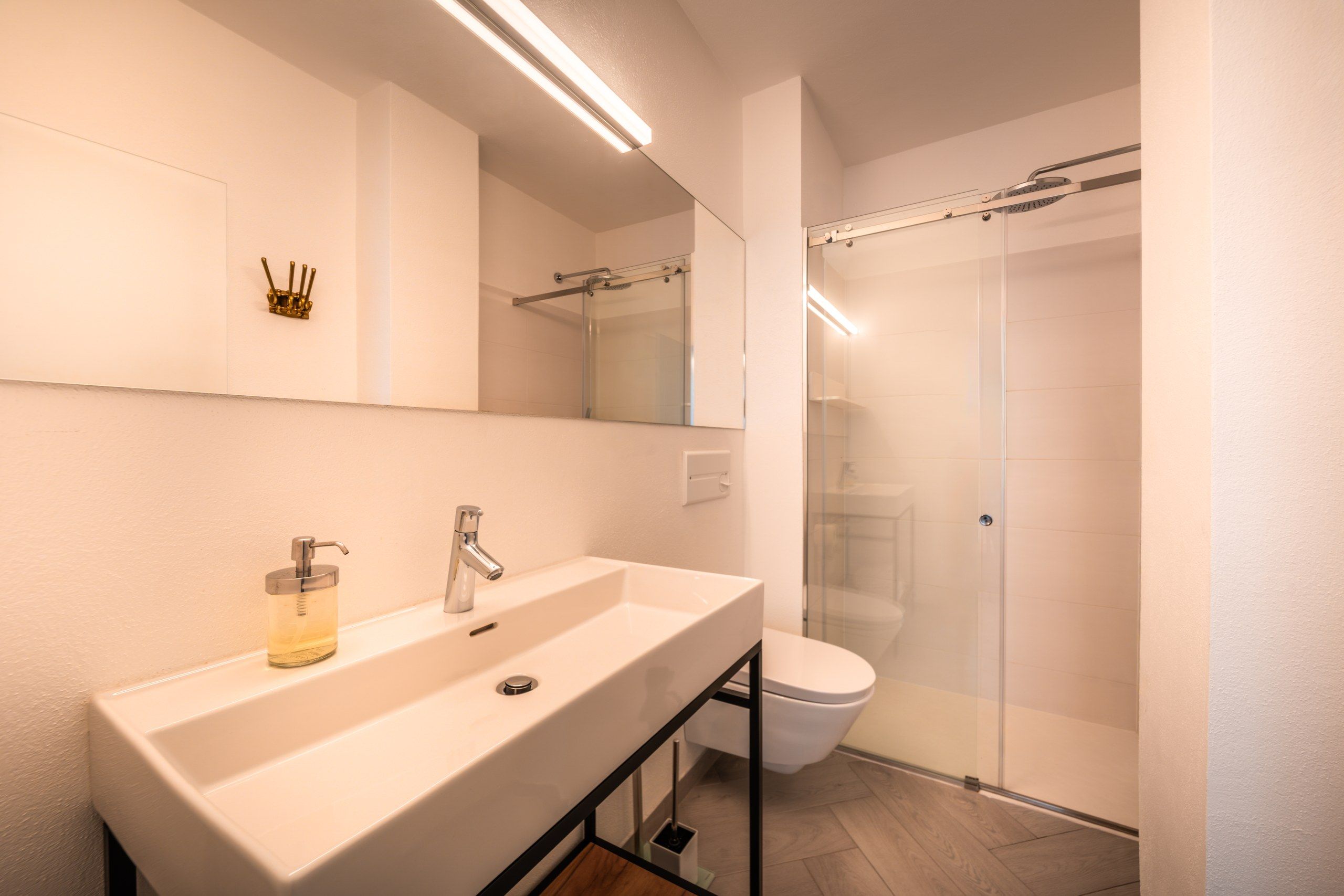 A modern bathroom with a large sink, a mirror, and a glass shower enclosure.