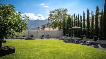 A well-maintained outdoor area with a grassy lawn, lounge chairs, and a view of mountains in the background.