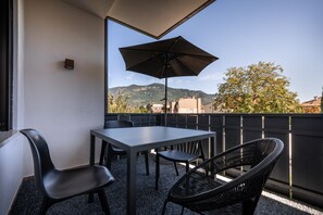 A balcony with a table and chairs, a large umbrella, and a view of the surrounding landscape. - 739G goldfinger+suites I Apartment Extraordinary 1 (Lana)