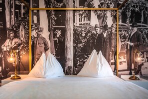 Una cama con dos almohadas blancas y una fotografía histórica blanco y negro de fondo.