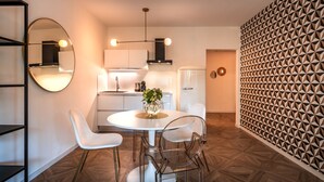 A modern kitchen with a round dining table, white chairs, and a decorative vase.