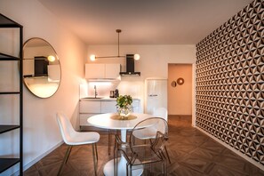 A modern kitchen with a round dining table, white chairs, and a decorative vase. - 739J goldfinger+suites I Apartment Individual 22 (Lana)