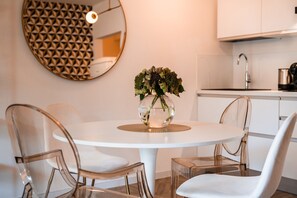 Una cocina moderna con armarios blancos, una mesa redonda con sillas y un jarrón decorativo con flores.