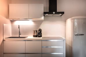 Una cocina moderna con un lavamanos de acero inoxidable, una cafetera y un refrigerador.