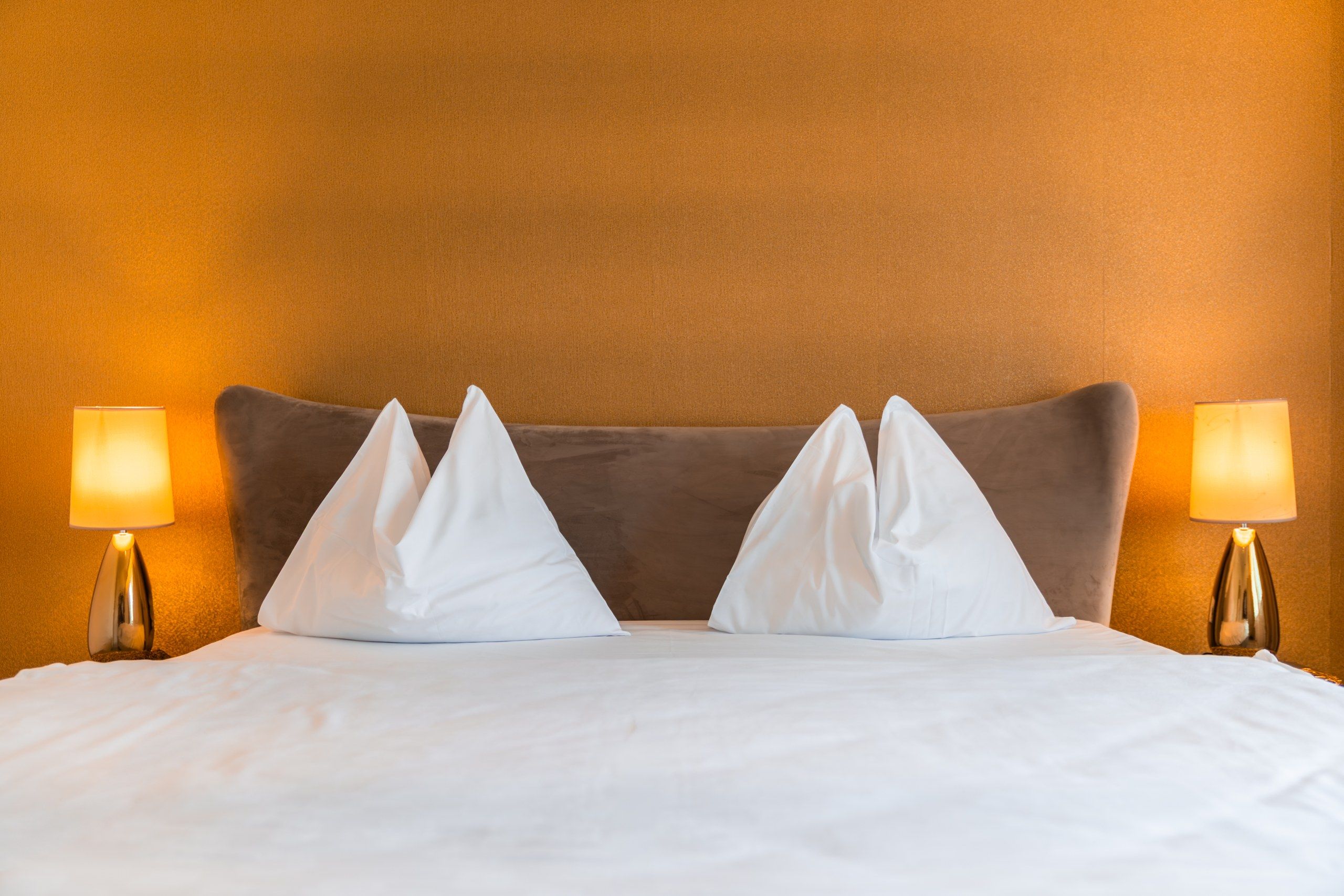 Ein Hotelzimmer mit einem Bett, zwei Nachttischlampen und einer strukturierten Wand.