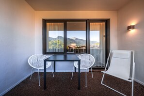 A small room with a table and two chairs, a window with curtains, and a wall-mounted light.