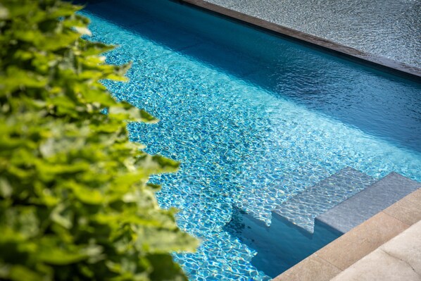 A clear blue pool with a tiled edge and a stone border.