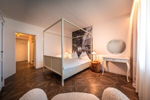 A four-poster bed with a night sky mural, a bedside table with a lamp, and a round mirror on a white dresser.