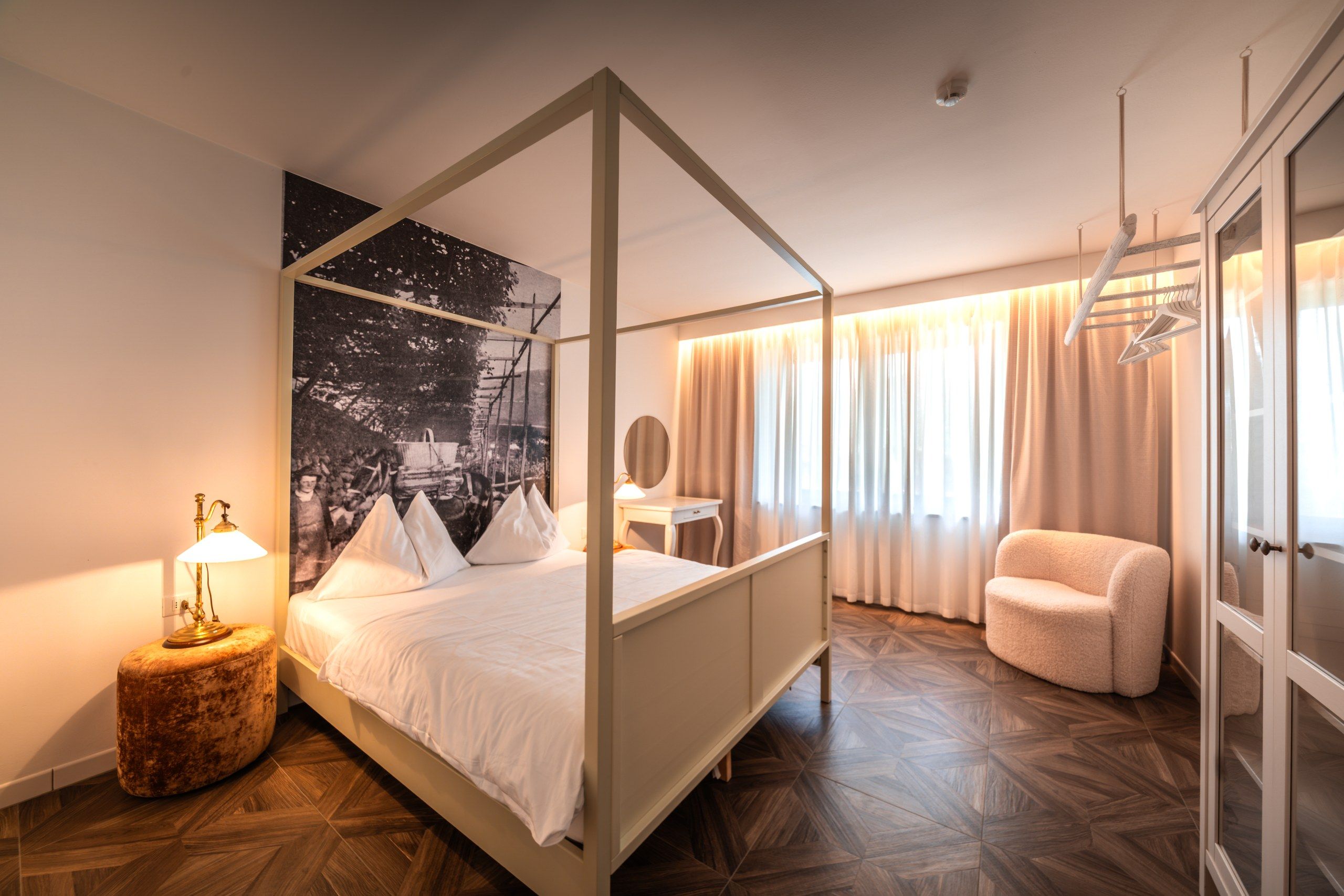 Un lit à baldaquin orné d’une fresque représentant un ciel étoilé, une lampe de chevet, une chaise et une armoire avec un miroir.