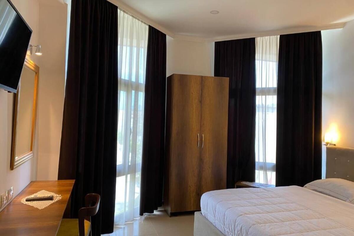 Una habitación de hotel con cama, armario de madera, escritorio con silla y televisor.