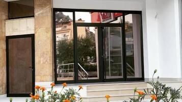 La entrada del Hotel Republikka, con un diseño moderno, presenta amplias puertas de cristal y una escalera visible que conduce a la recepción.