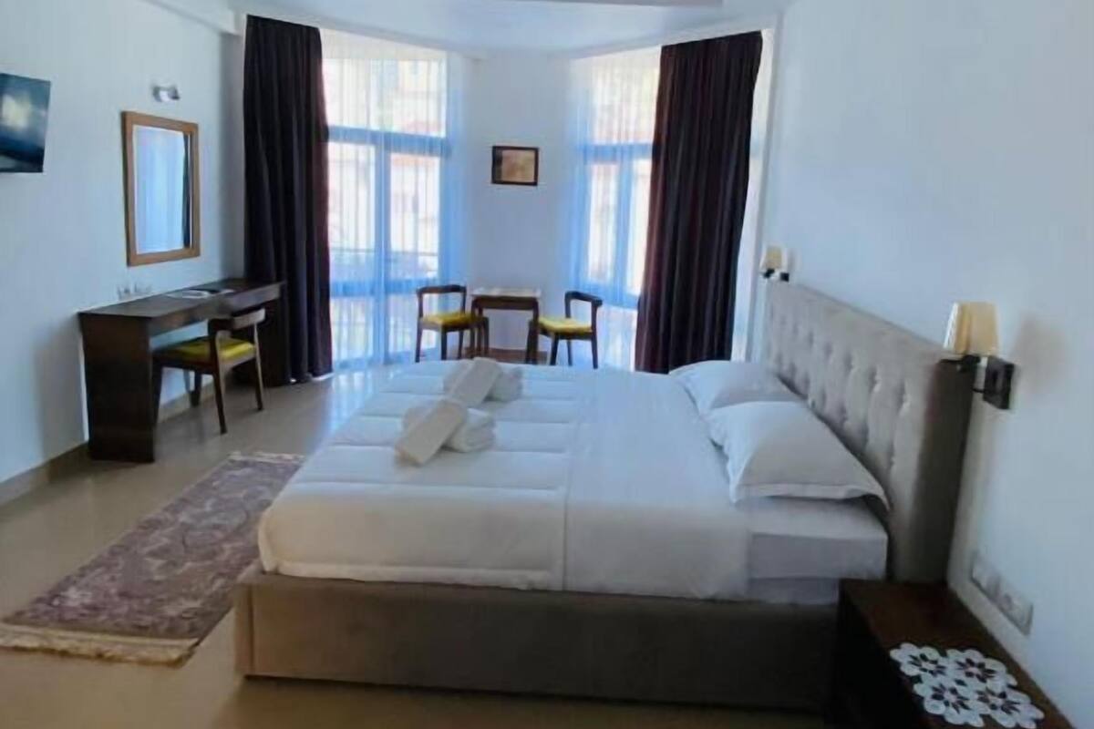 Habitación de hotel con una cama grande, un escritorio, dos sillas y una mesita.